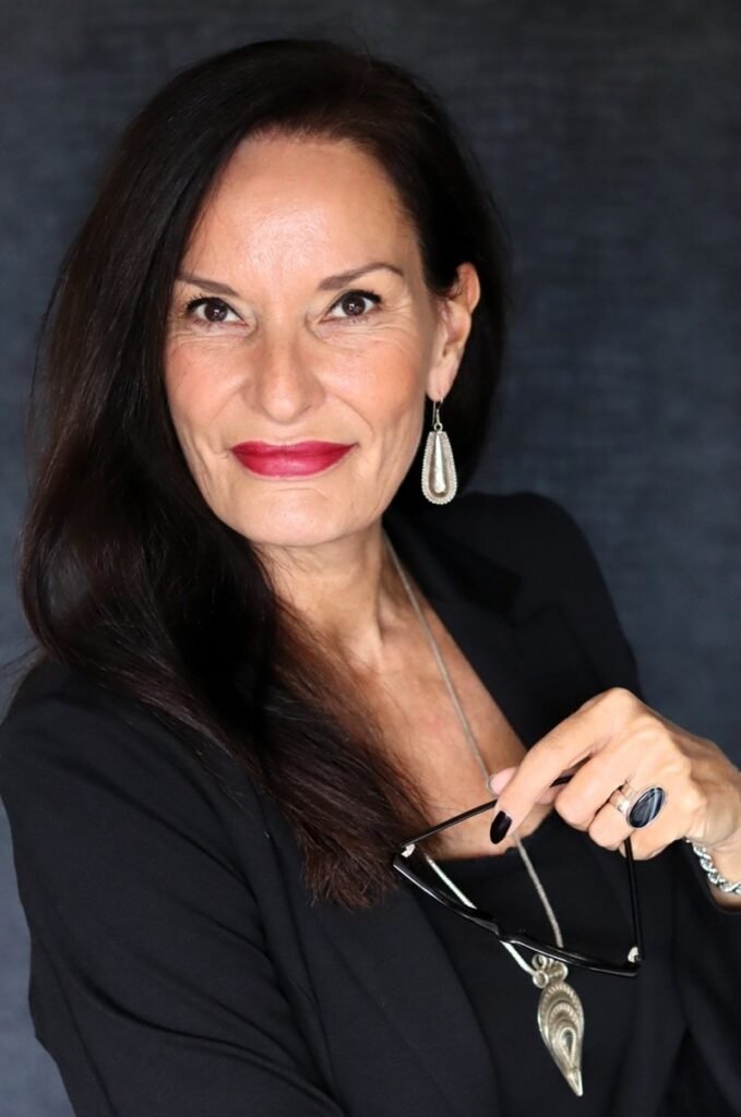 Aglaia wearing a black suit with bold red lipstick and silver statement jewelry, illustrating how to style black intentionally